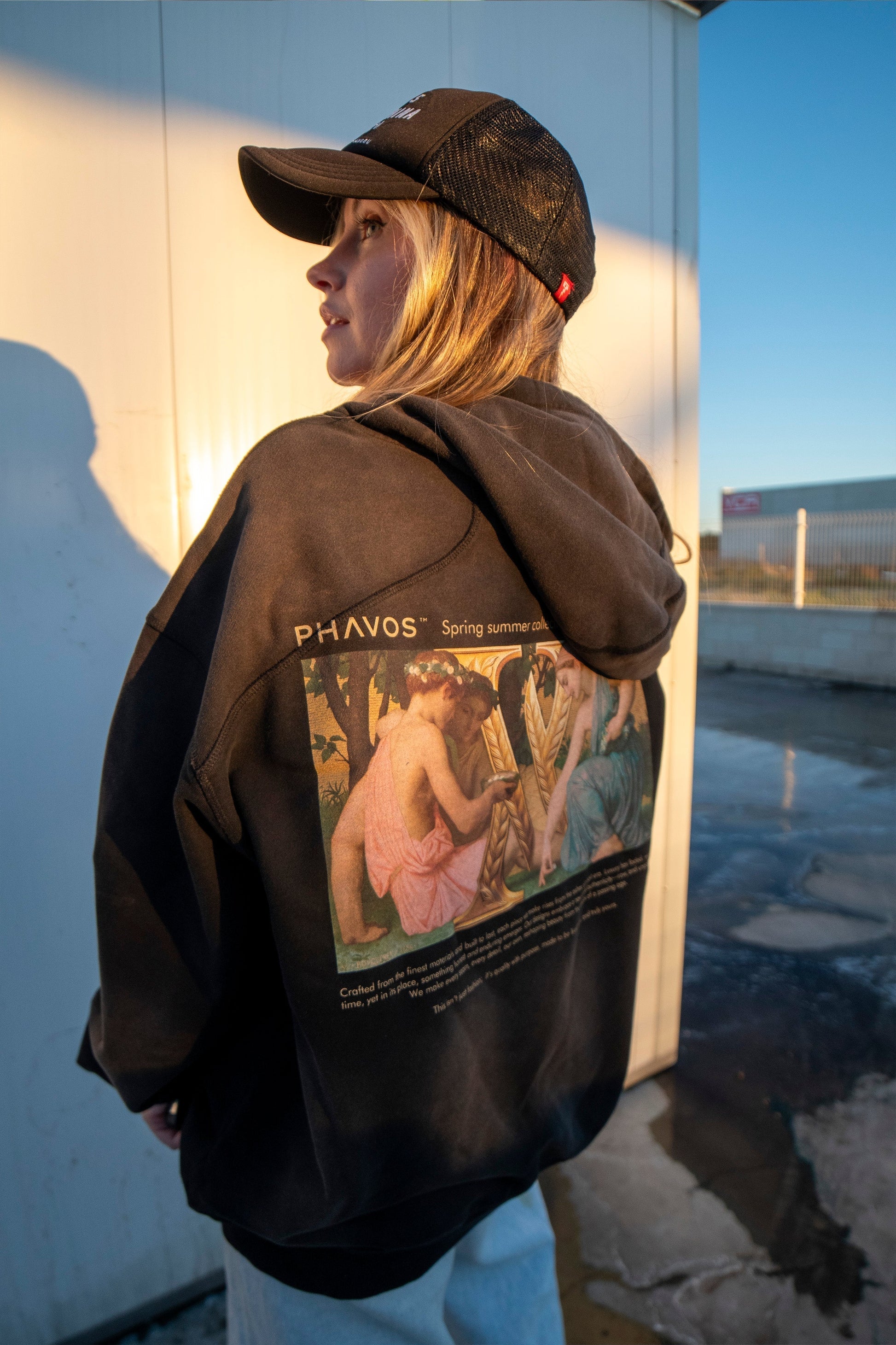 Female model wearing a luxury streetwear hoodie at sunset, silhouette fading into golden light.